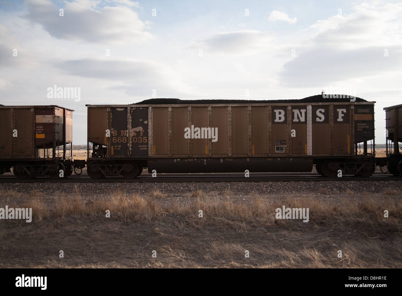 BNSF train box car filled with coal and traveling on train tracks Stock