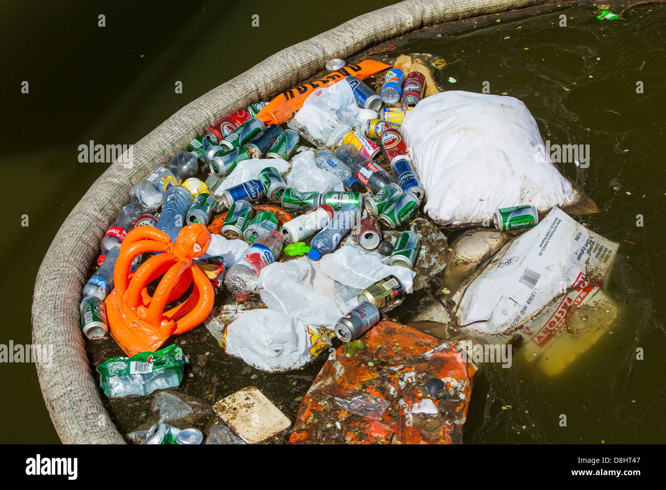 Rubbish up against a litter trap on a canal in Amsterdam, Netherlands. Stock Photo