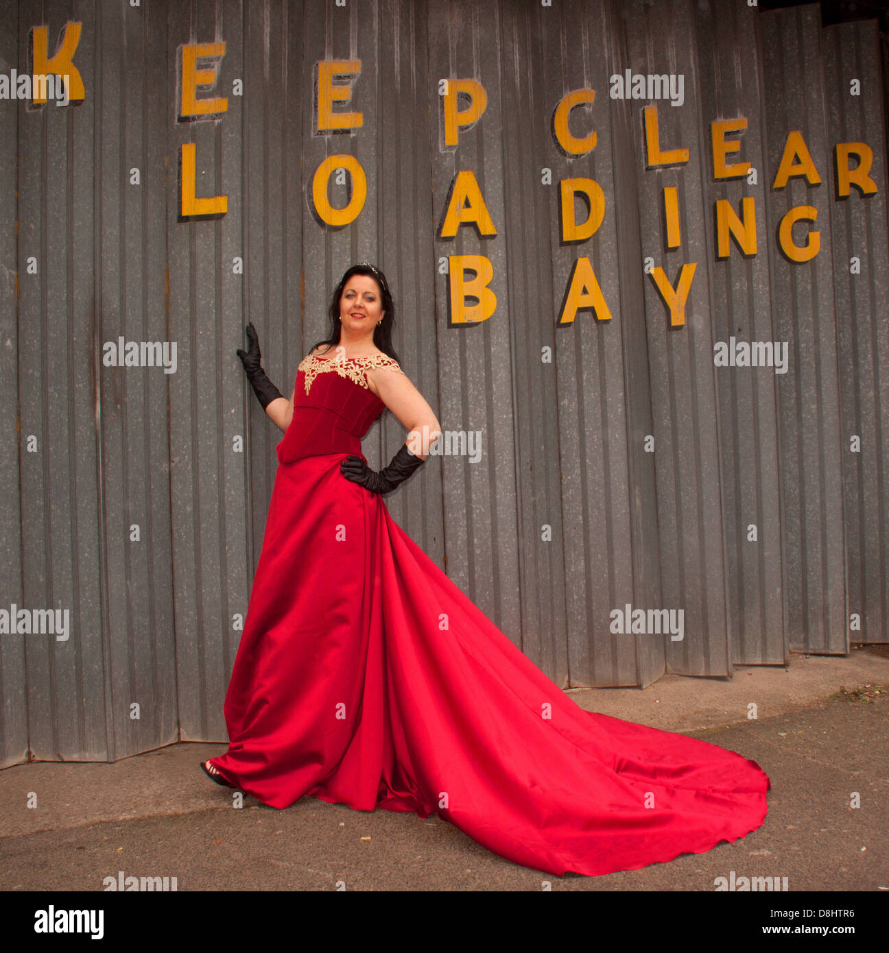 Woman in red dress in front of Keep Clear Loading Bay sign Stock Photo