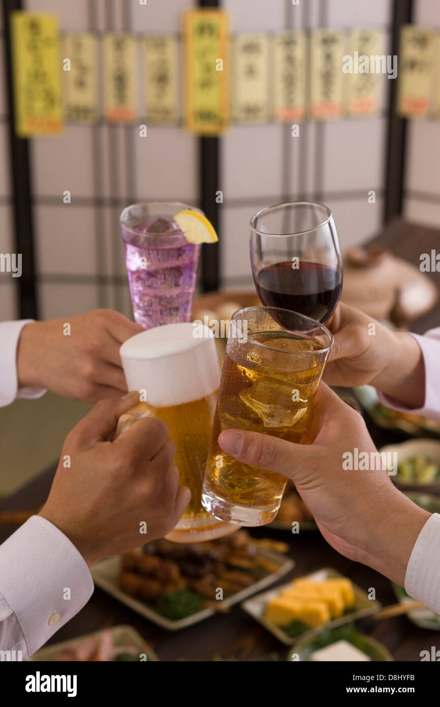 Four People Toasting with Each Other With Various Drinks at Izakaya Stock Photo
