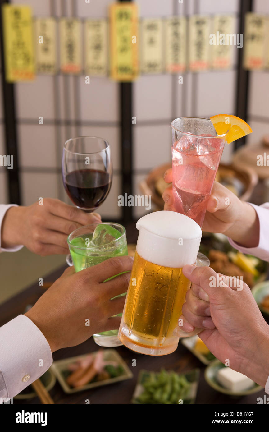 Four People Toasting with Each Other With Various Drinks at Izakaya Stock Photo