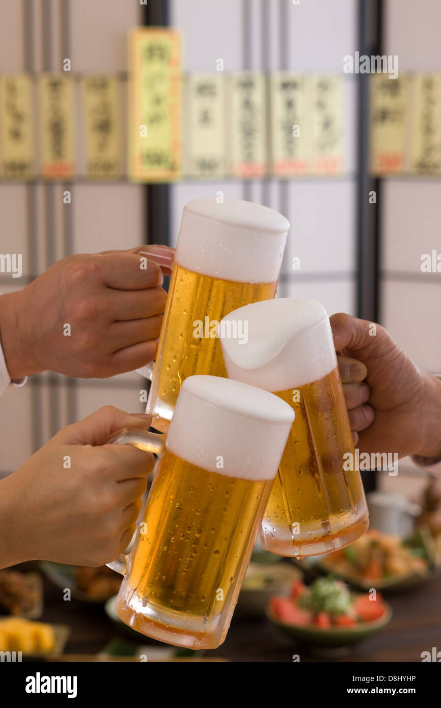 Three People Toasting with Beer at Izakaya Stock Photo