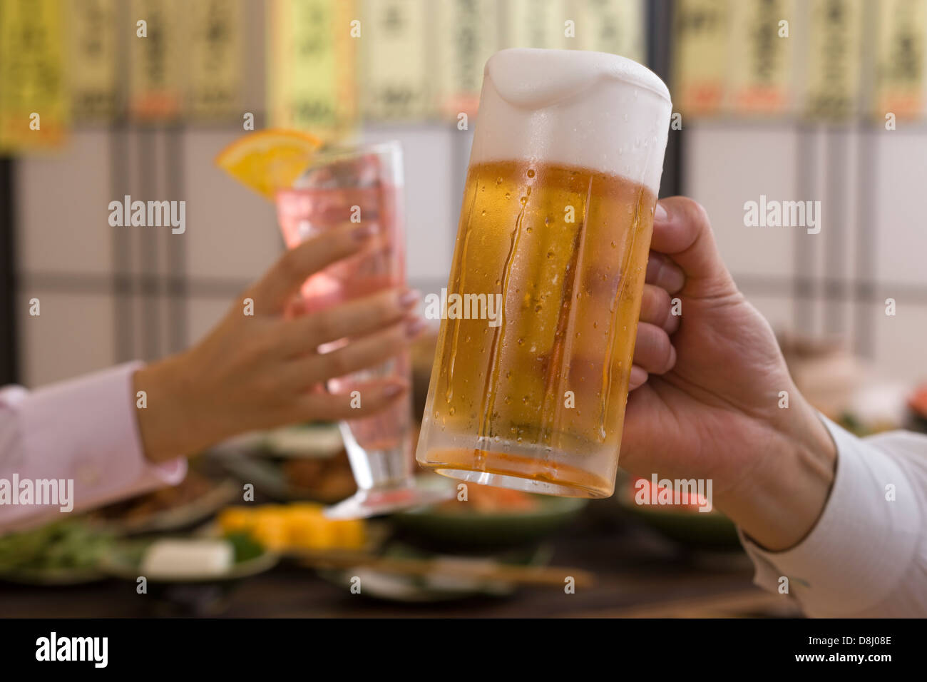 Two People Toasting with Beer and Cocktail at Izakaya Stock Photo