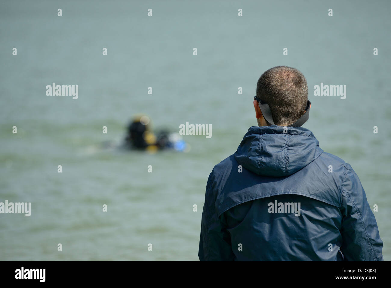 Male spectator watching a diver in the background Stock Photo