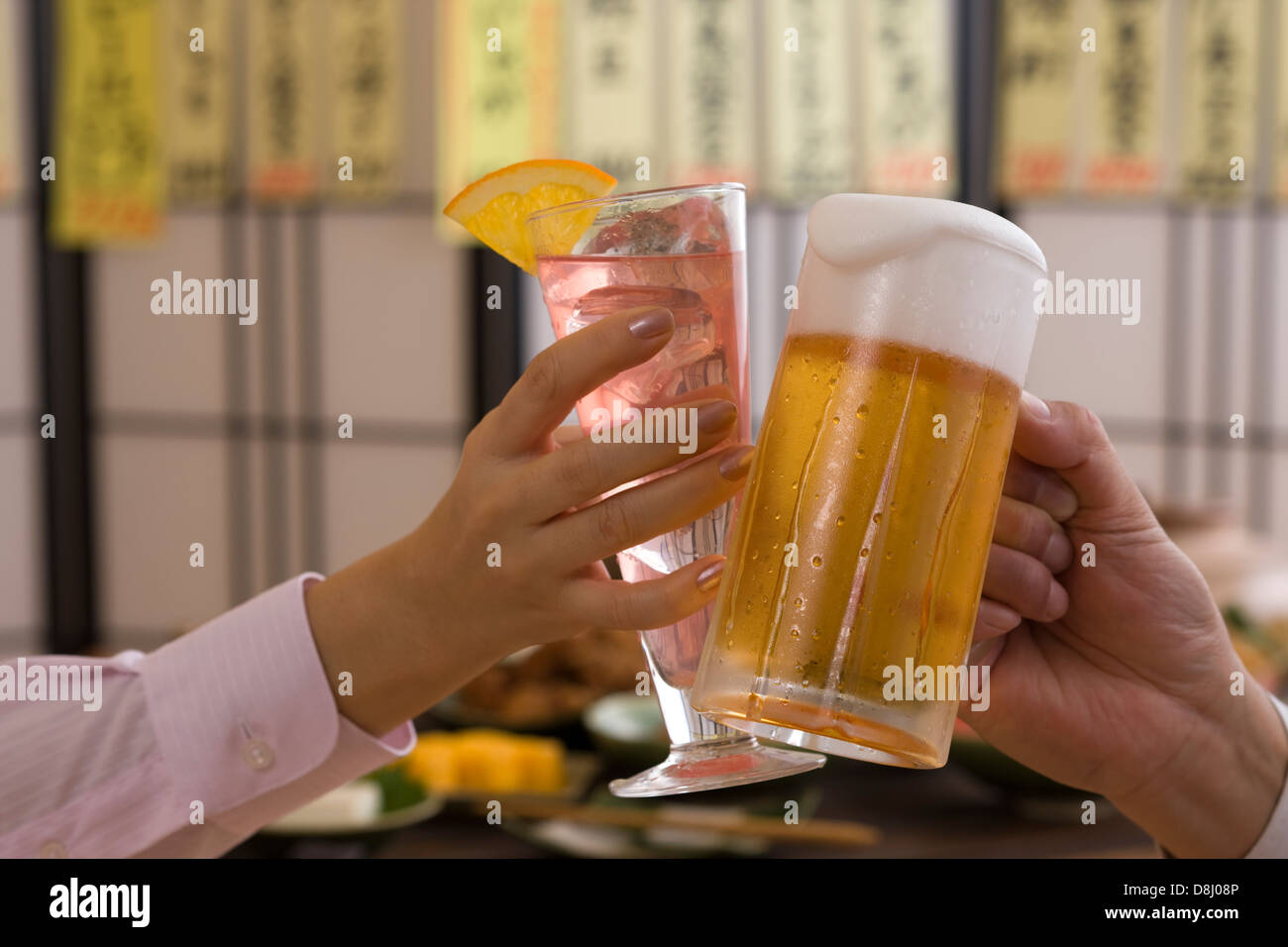 Two People Toasting with Beer and Cocktail at Izakaya Stock Photo