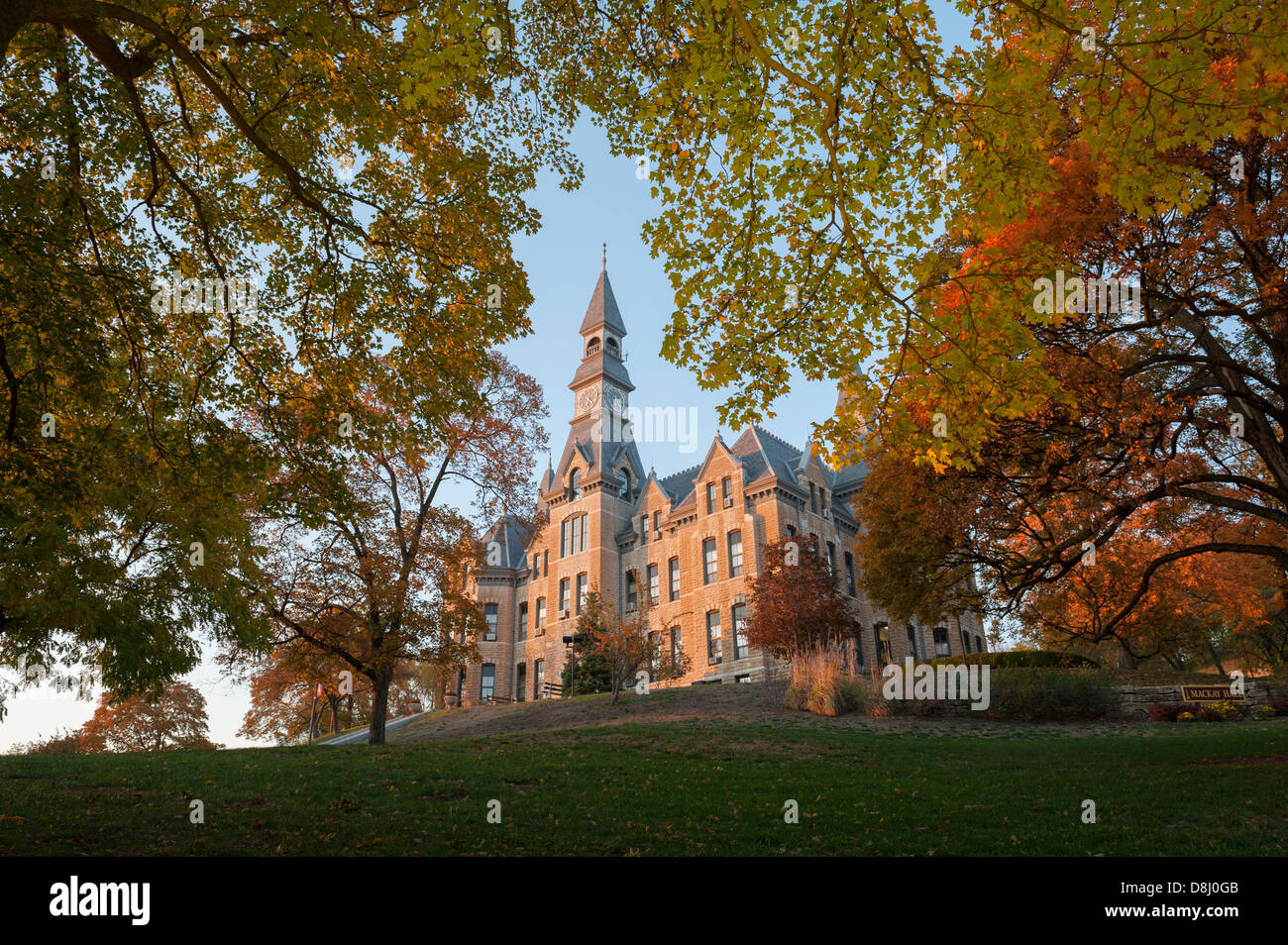 A 19th century college building surrounded by trees in Fall colors, photographed at sunset. Stock Photo