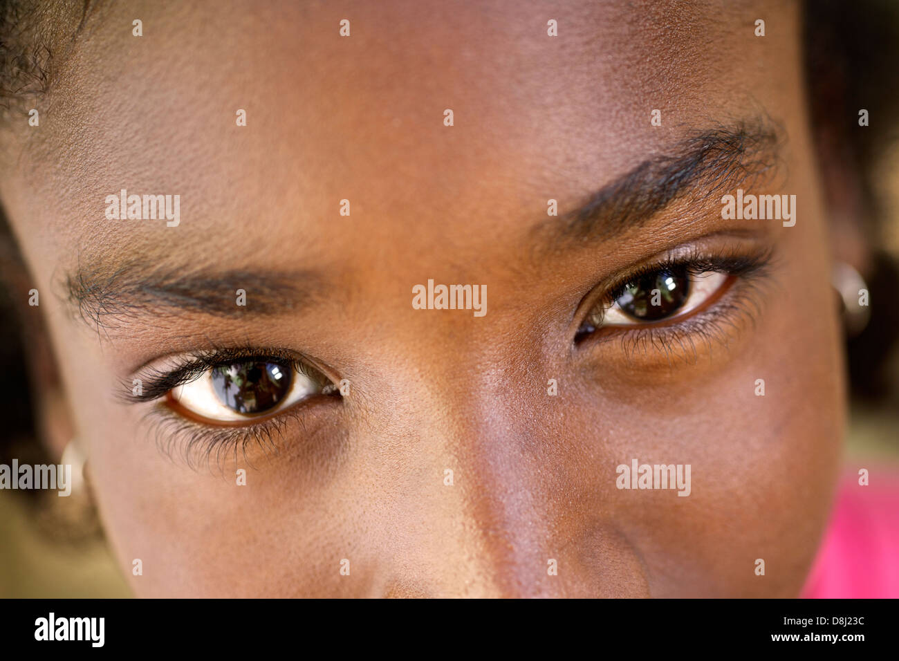 Closeup of eyes of pretty happy young african girl looking at camera and smiling Stock Photo