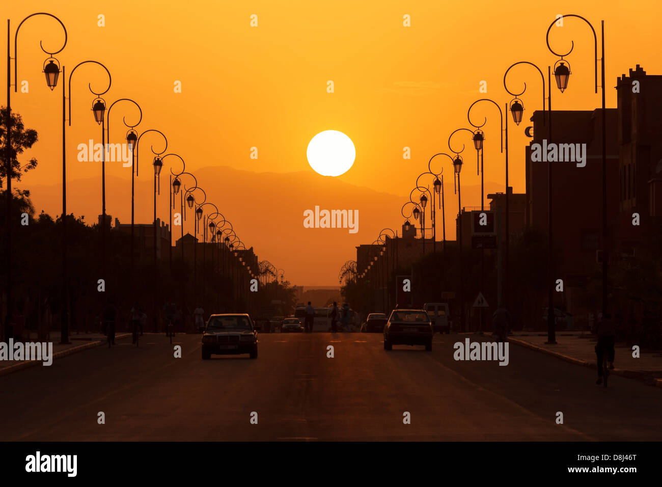 Silhouette city scene with street and street lamps against sunset. Stock Photo