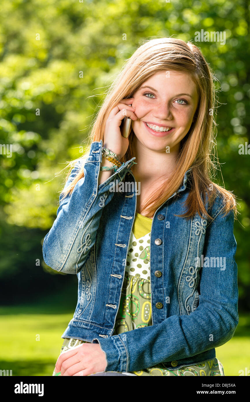 Lively young girl talking on her phone outside during spring Stock Photo