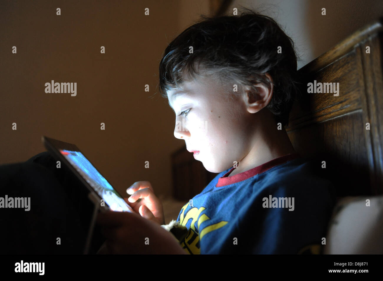 An 8 year old boy playing a computer game on his Apple IPAD in his ...