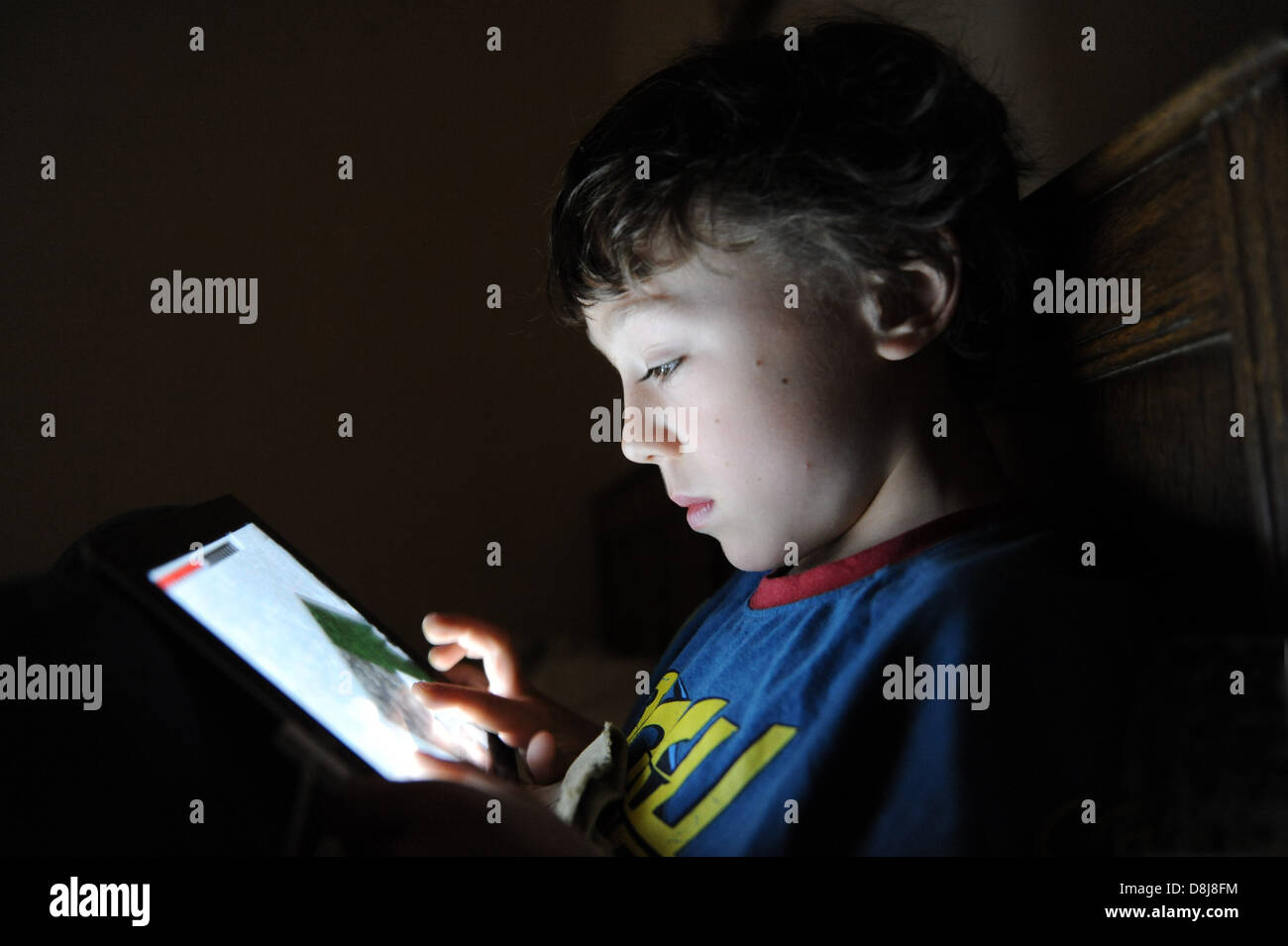 An 8 Year Old Boy Playing A Computer Game On His Apple Ipad