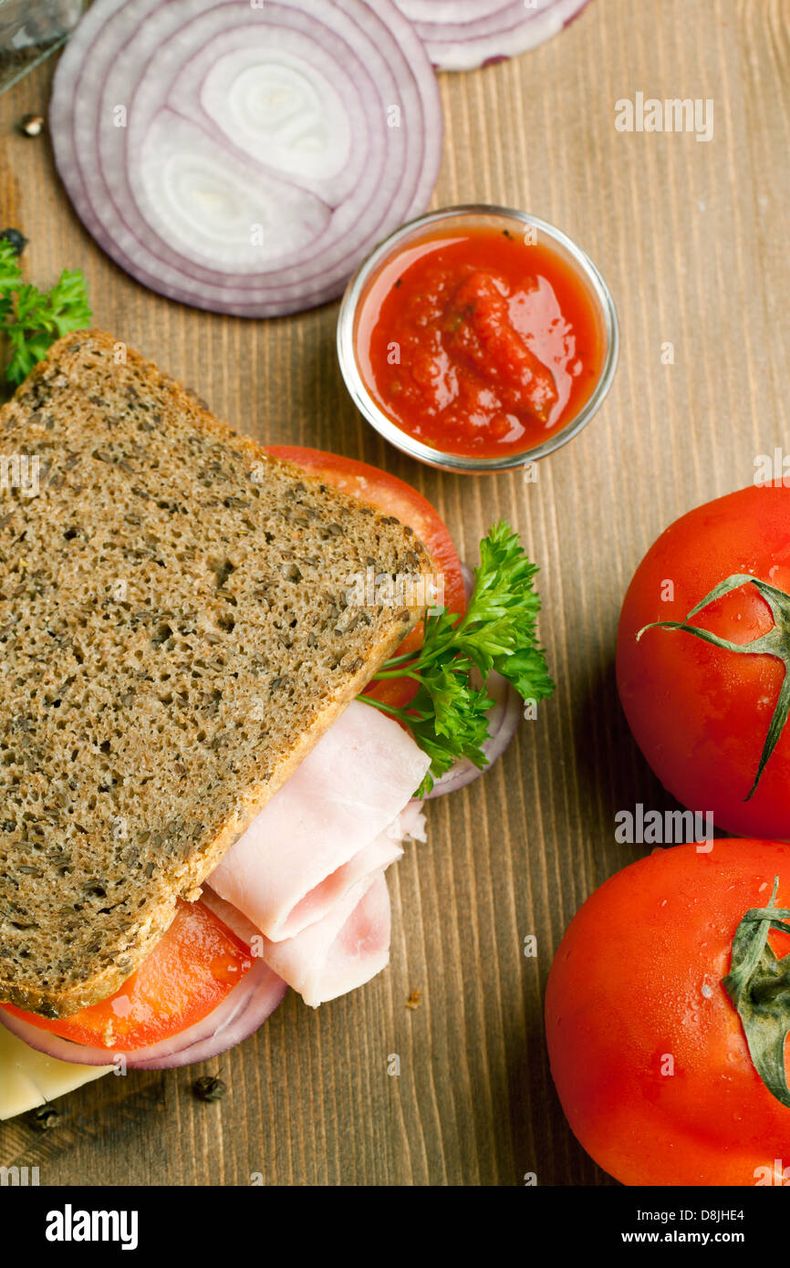 Top view on fresh sandwich with ham, tomatoes, sliced onion and ketchup