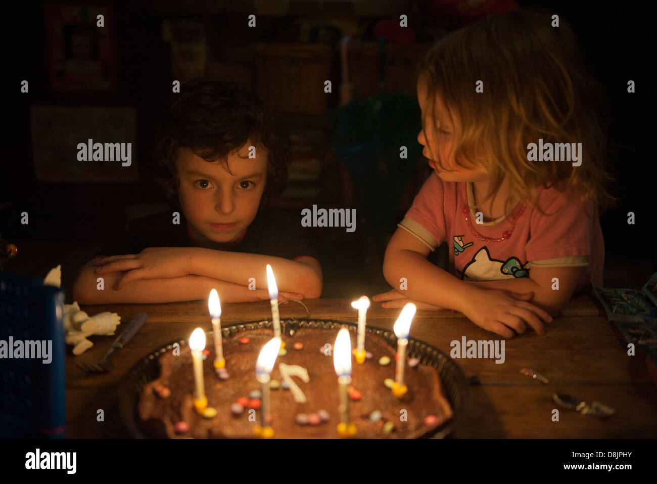 Little boy preparing to blow out candles on birthday cake as younger