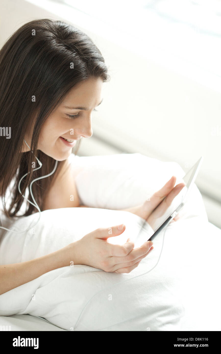 Young woman holding digital tablet while using a headphone in her bedroom Stock Photo