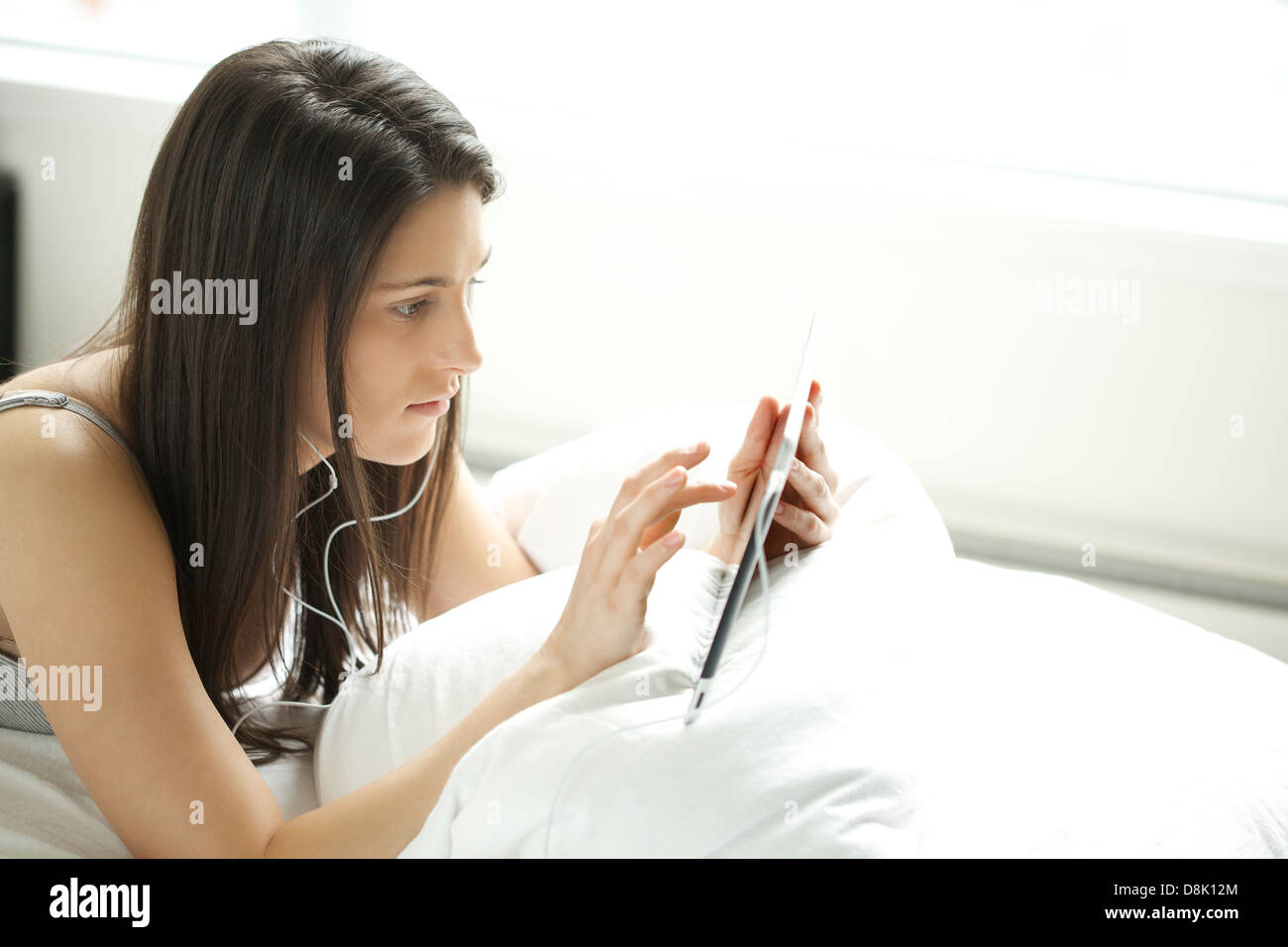 Young woman holding digital tablet while using a headphone in her bedroom Stock Photo