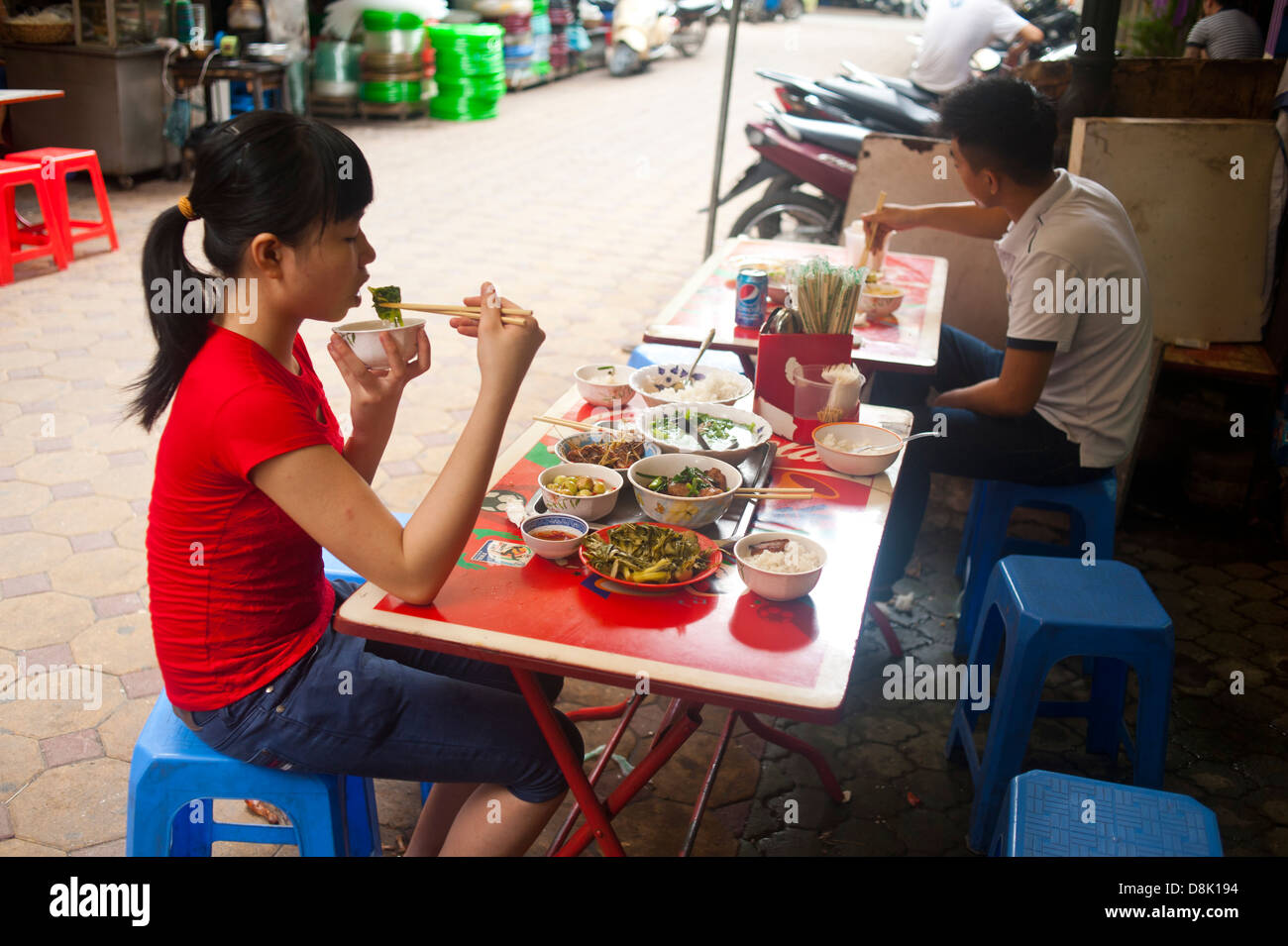 Hanoi, Vietnam - Young girl eating food on the street Stock Photo