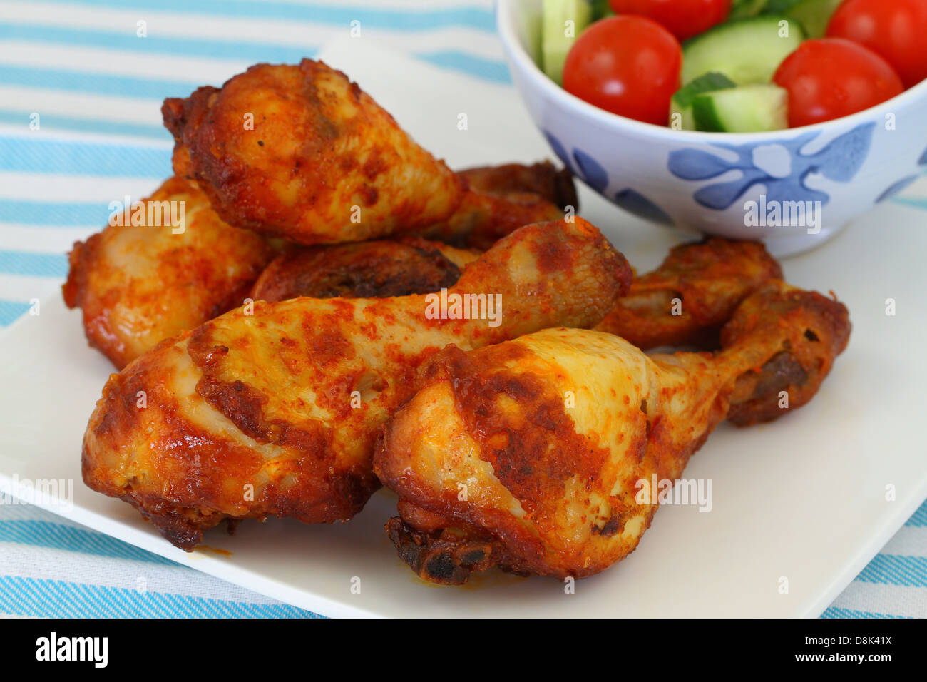 Roasted chicken drumsticks on vintage plate, close up Stock Photo