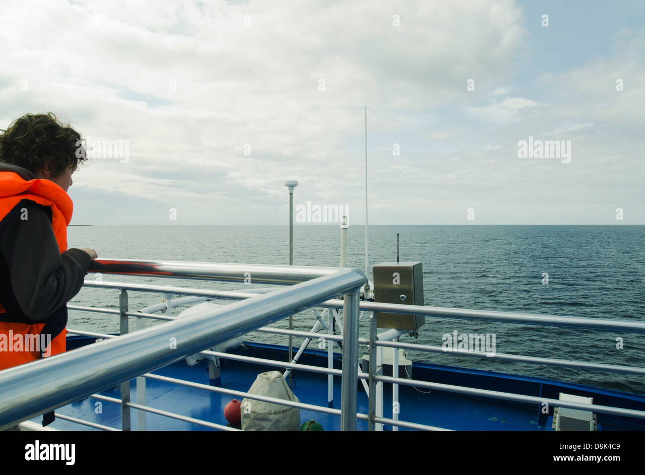 Boy watching the horizon, on the upper deck of a boat Stock Photo