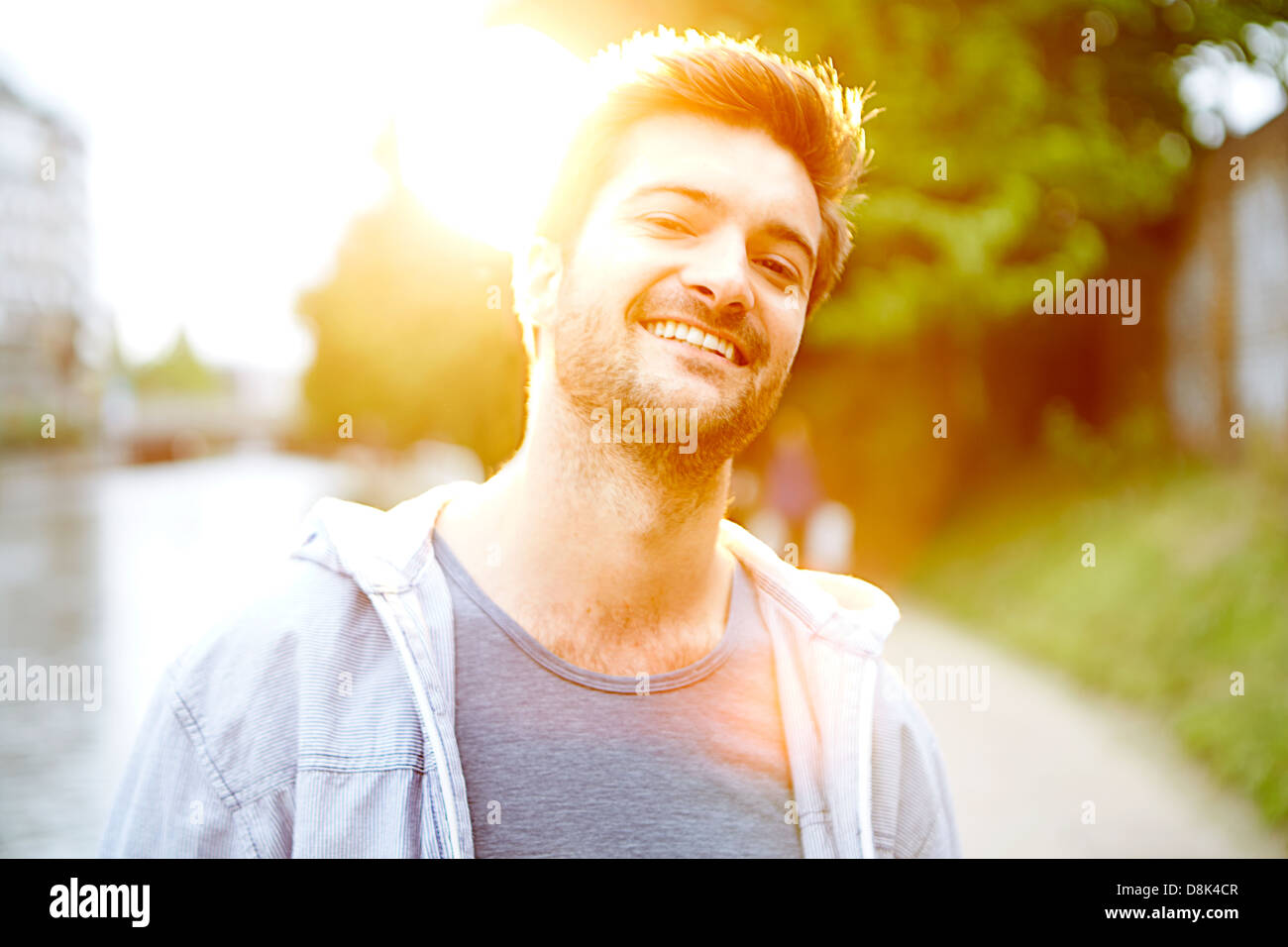 laughing young man with by canal sunlight lens flare Stock Photo