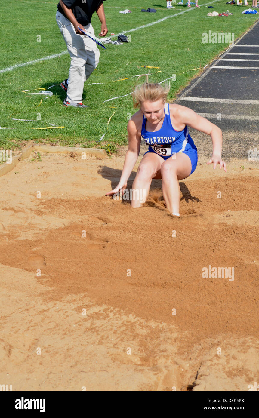Girl lands in the sand in a high jump during a track and field event