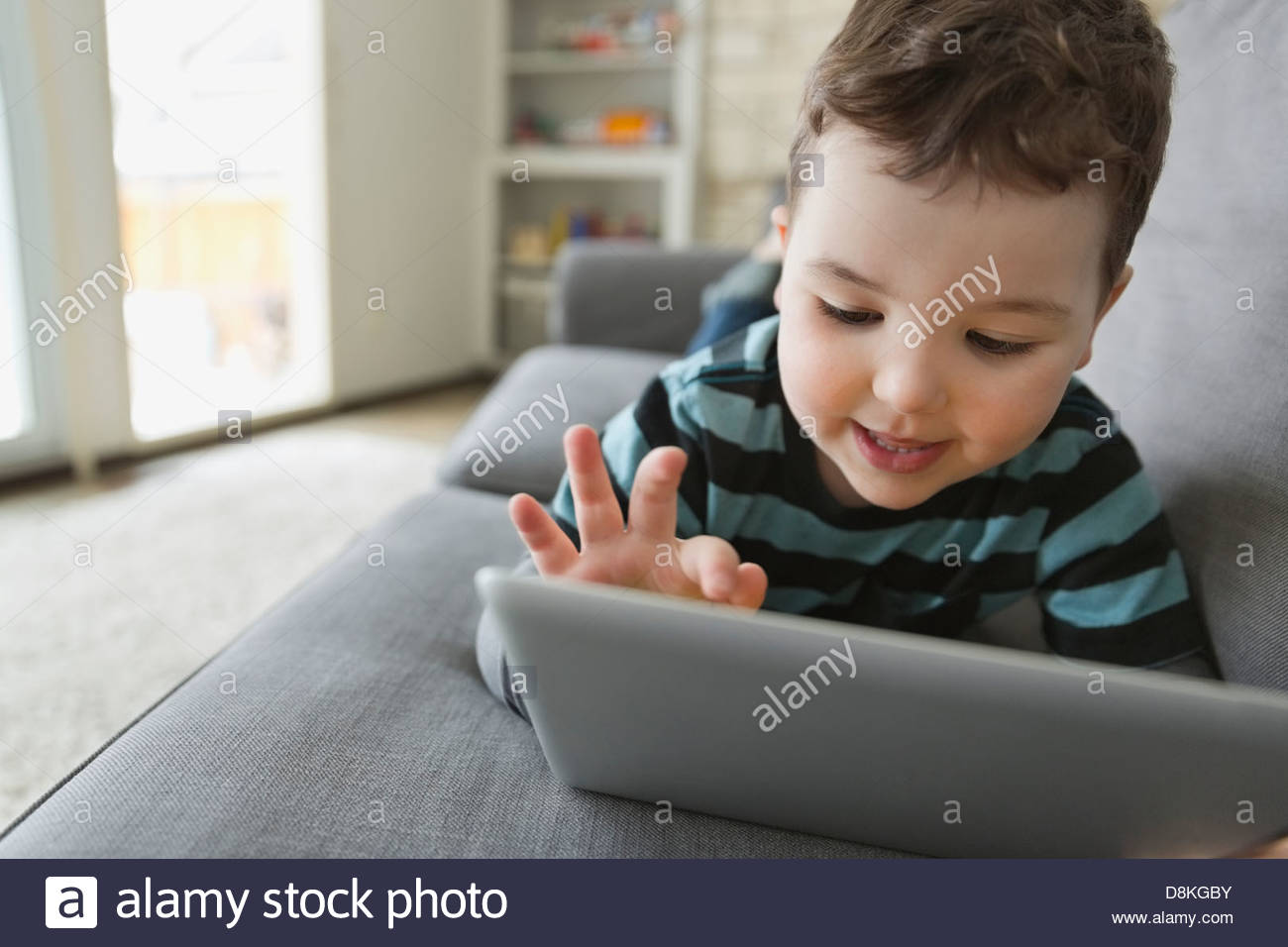 Little boy lying on sofa using digital tablet Stock Photo - Alamy