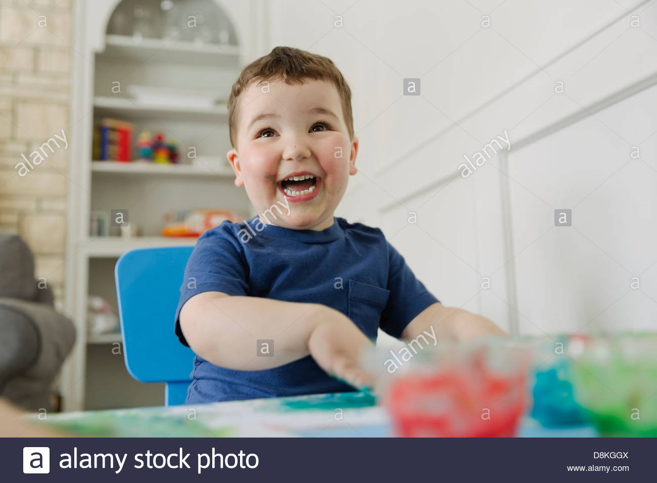 Laughing boy finger painting at home Stock Photo