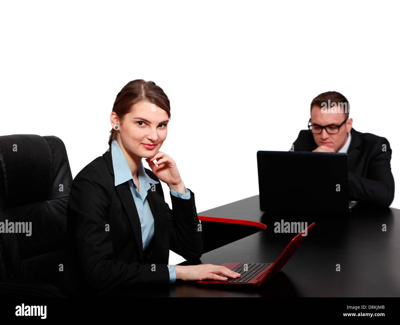 Young business colleagues working on their laptops at the office desk, isolated against a white background. Stock Photo