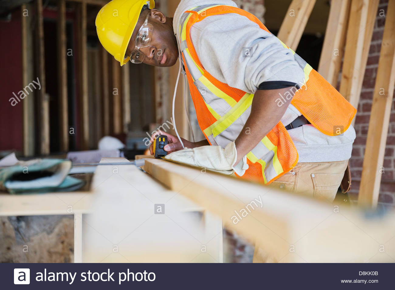 Tradesman measuring lumber at construction site Stock Photo
