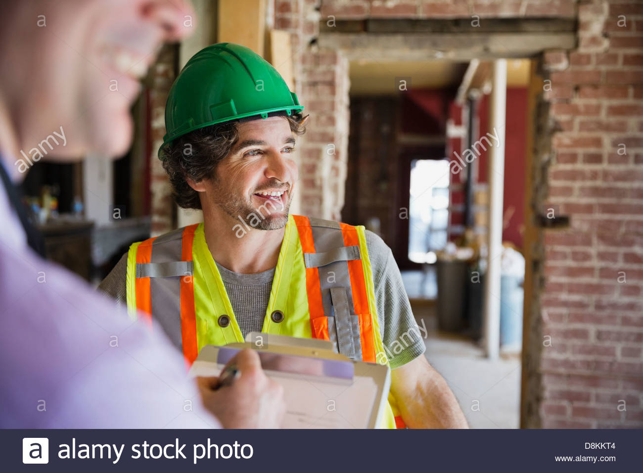 Smiling tradesman talking to architect at construction site Stock Photo