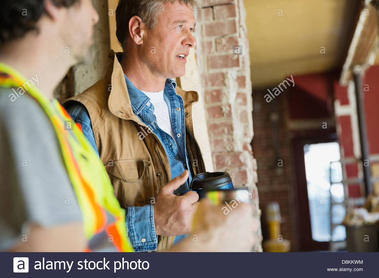 Foreman and tradesman taking coffee break at construction site Stock Photo