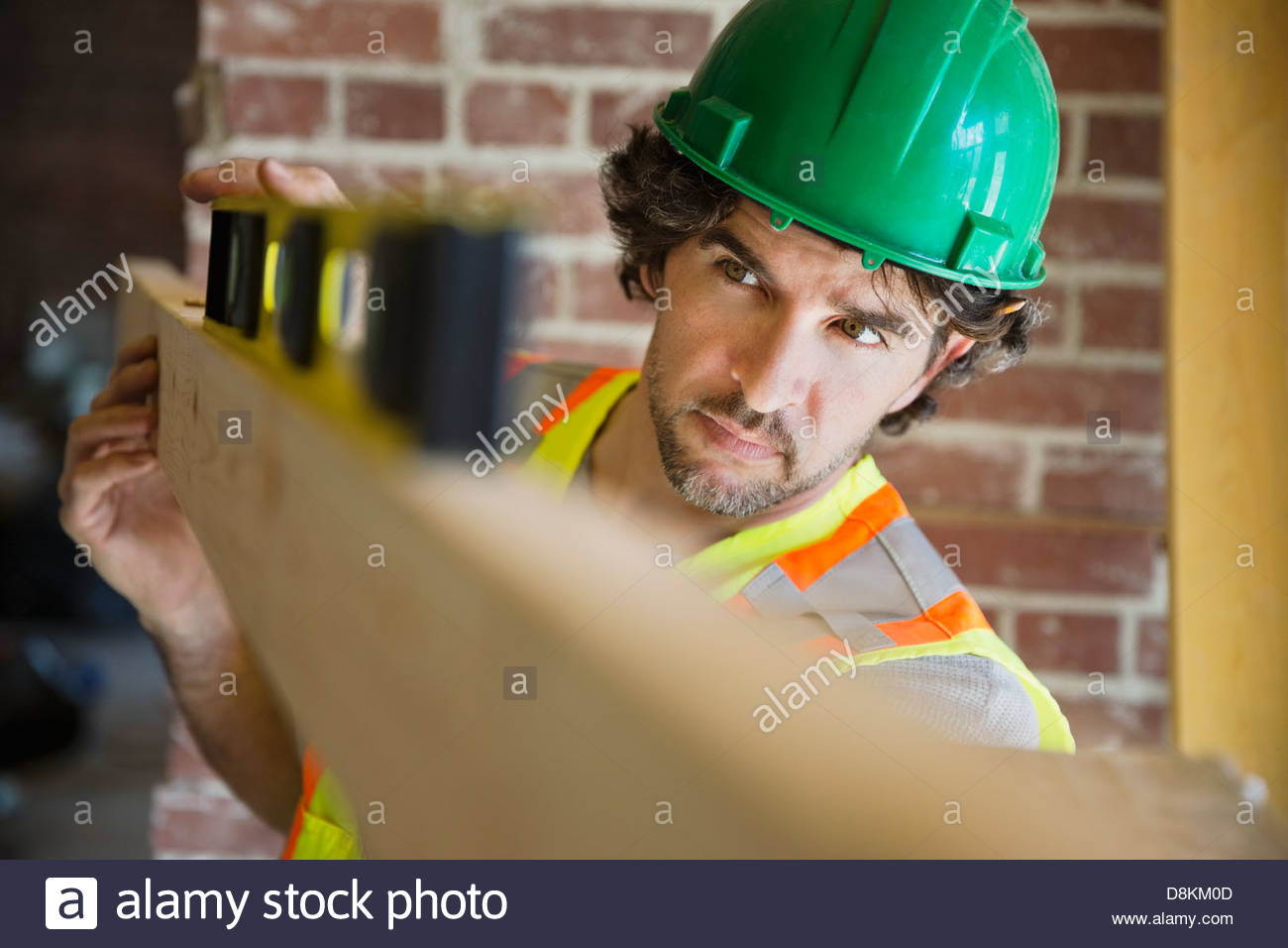 Tradesman leveling wooden plank at construction site Stock Photo