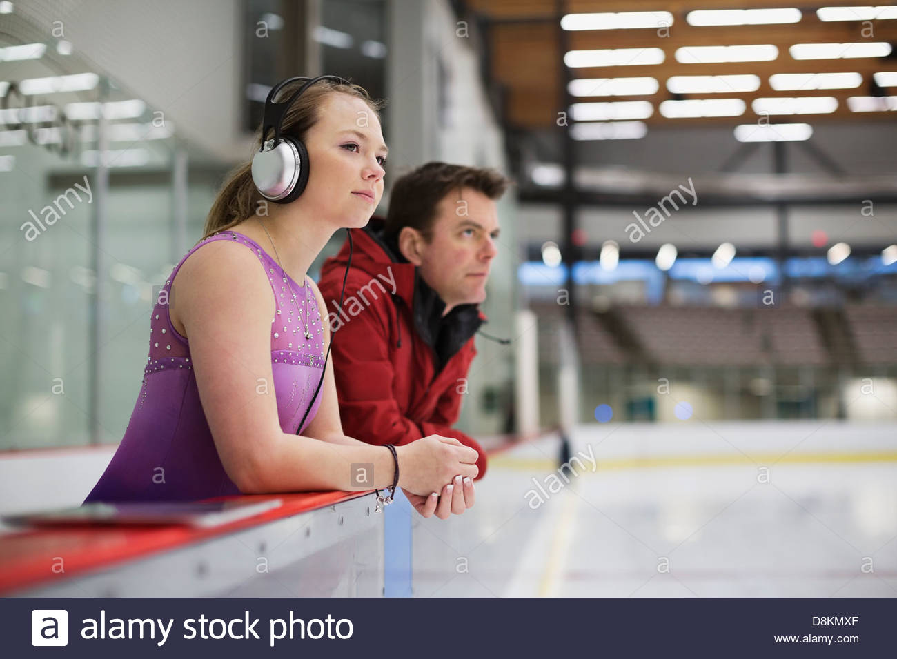 Female figure skater with coach preparing for routine in skating rink