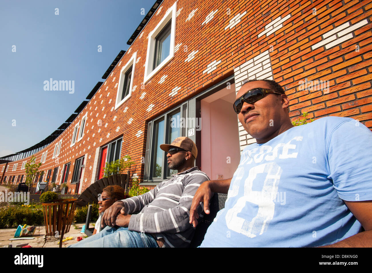 A family in front of their house in Almere with solar PV panels on the roof. Stock Photo