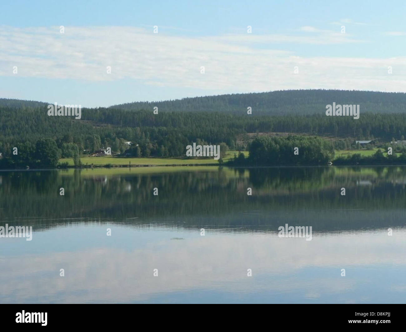 A calm, reflective lake surface that mirrors the surrounding landscape ...