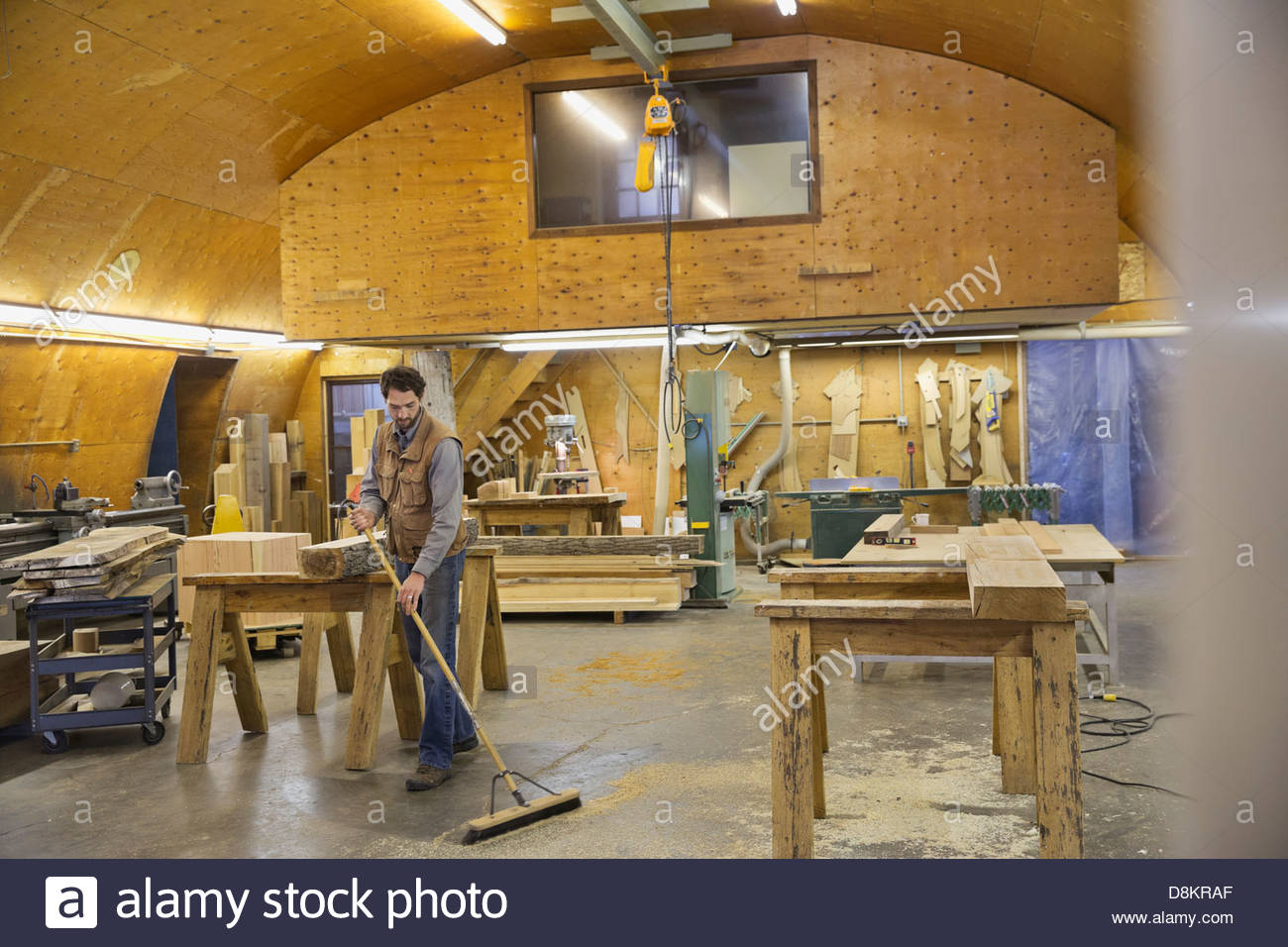 Carpenter sweeping sawdust with broom in Stock Photo Alamy