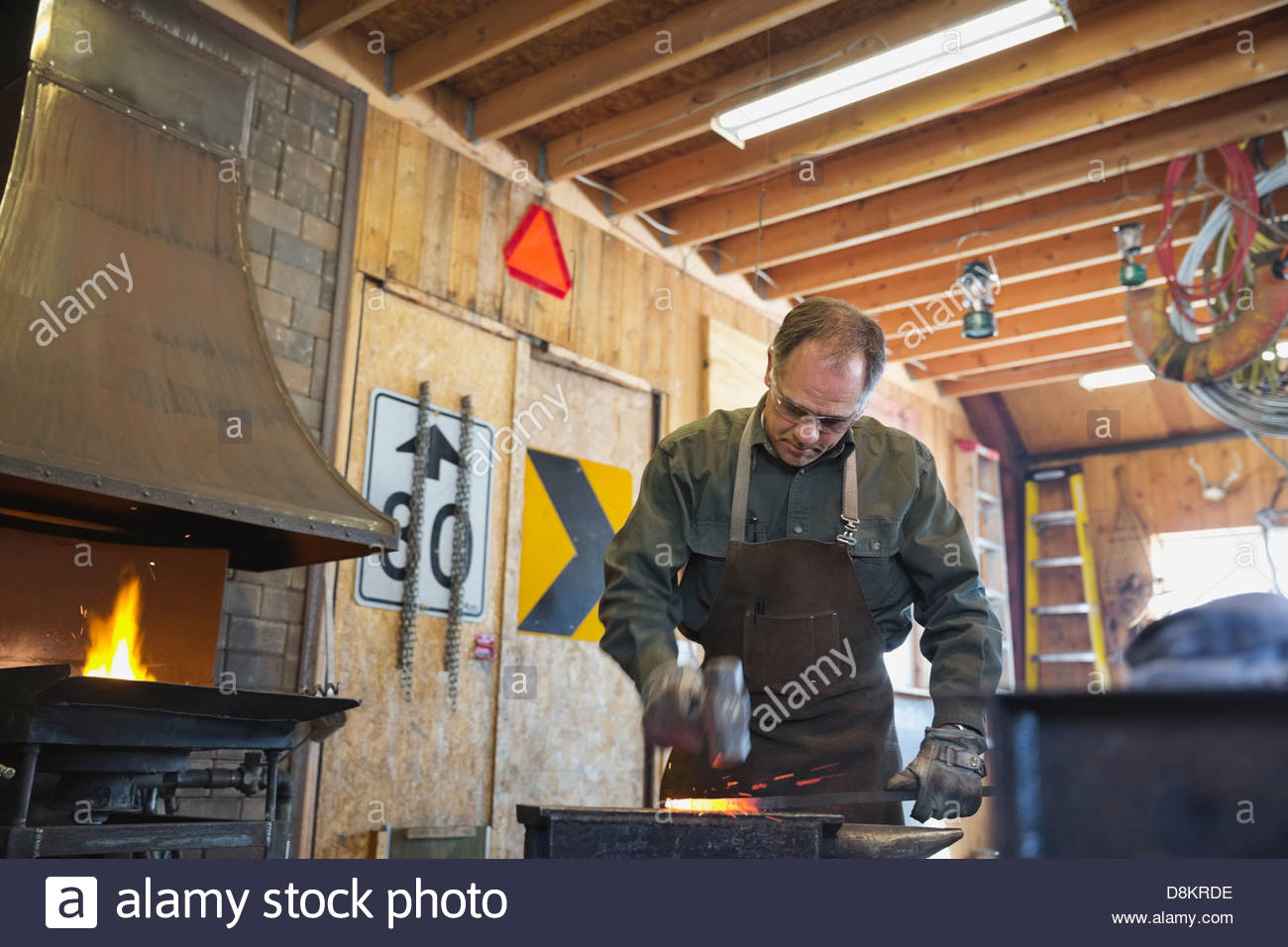 Metalworker hammering hot metal at workshop Stock Photo