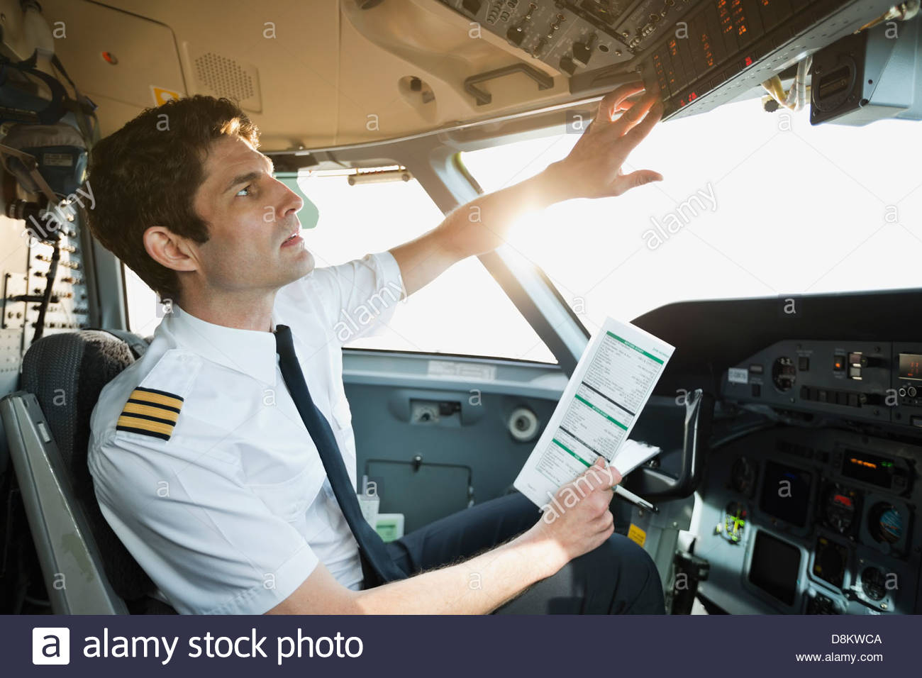 Male pilot checking control panel in airplane cockpit Stock Photo Alamy