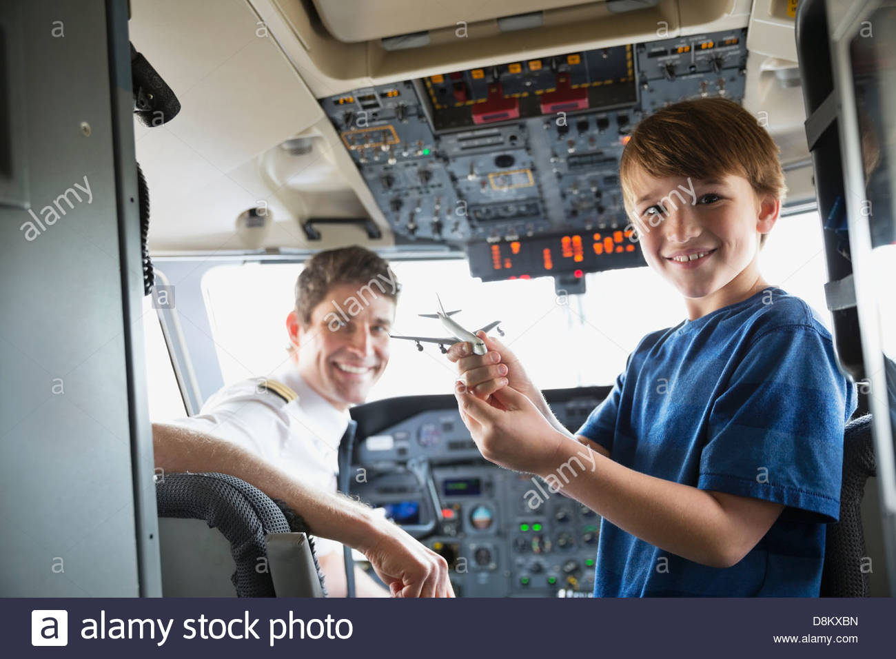 Portrait of boy holding toy plane with male pilot in airplane cockpit Stock Photo