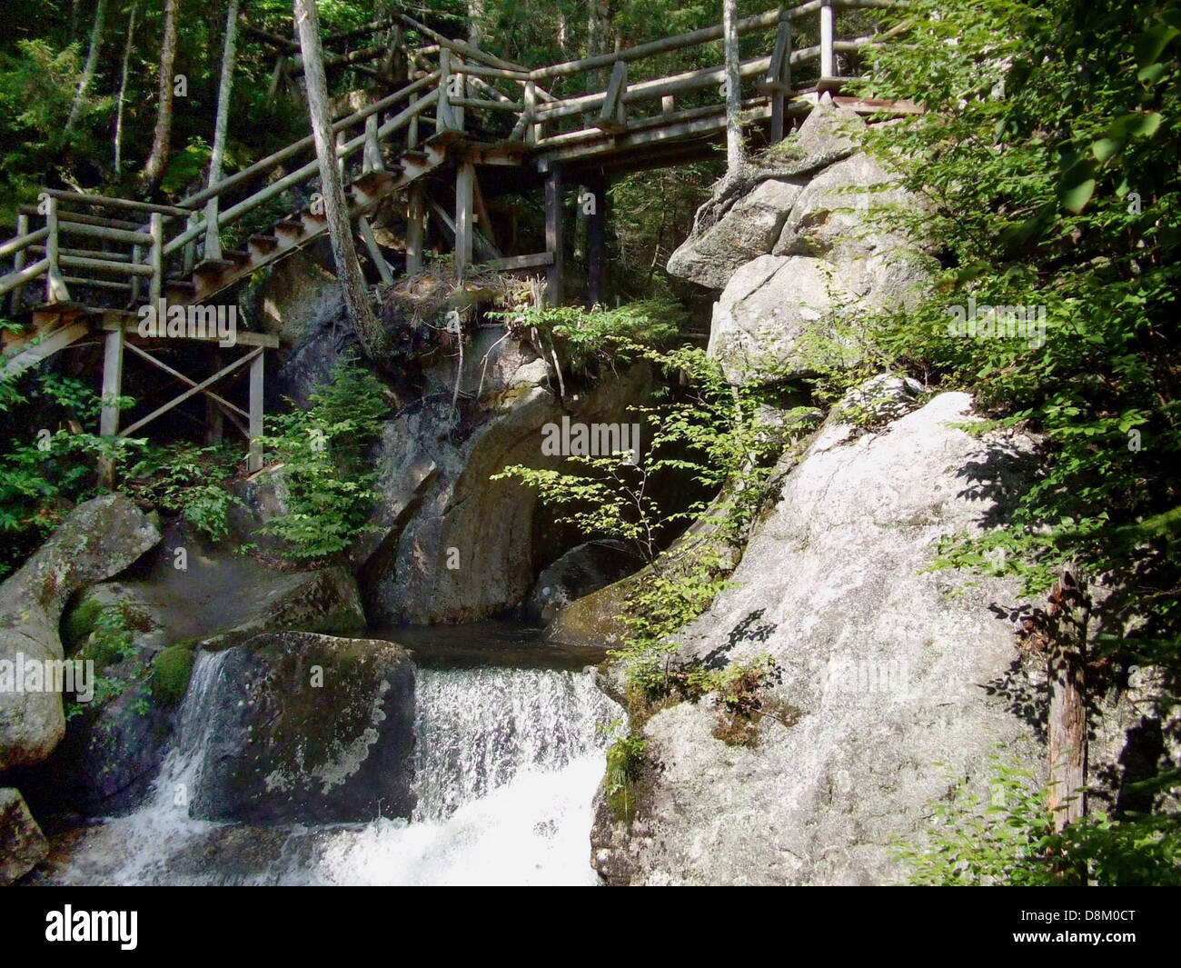 Bridge En Rocks A wooden bridge spans across water and rocks in a forest setting ...
