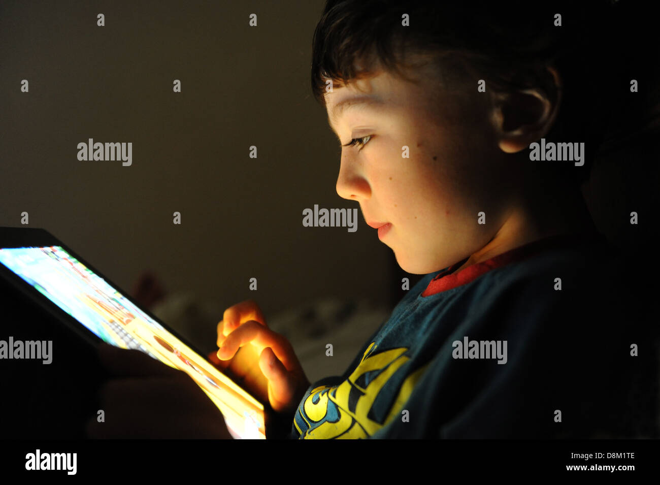 An 8 year old boy playing a computer game on his Apple IPAD in his ...
