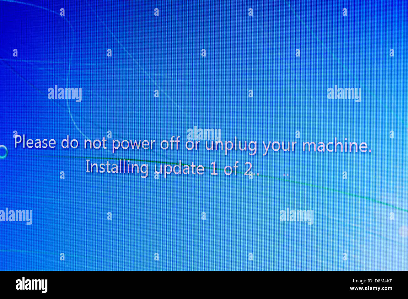 Windows Update message on screen 'Please do not power off or unplug your machine.  Installing update 1 of 2' Stock Photo