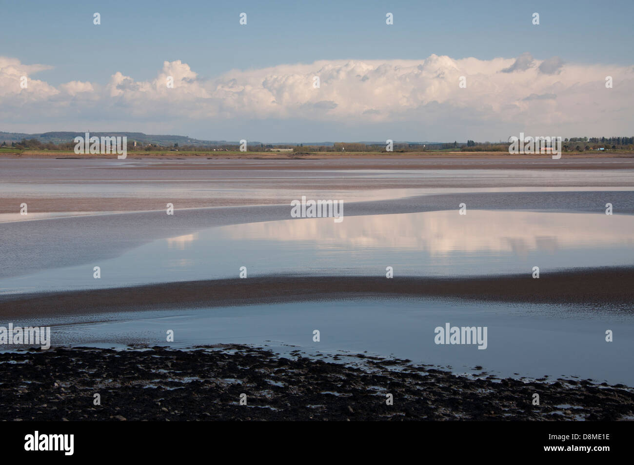 River Severn, flood defences, rocks, boulders, bank, mud, lichen, skyscape, blue sky, white and gray clouds Stock Photo