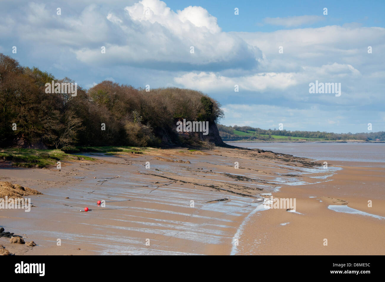 River Severn, flood defences, rocks, boulders, bank, mud, lichen, skyscape, blue sky, white and gray clouds, shrubs, trees Stock Photo