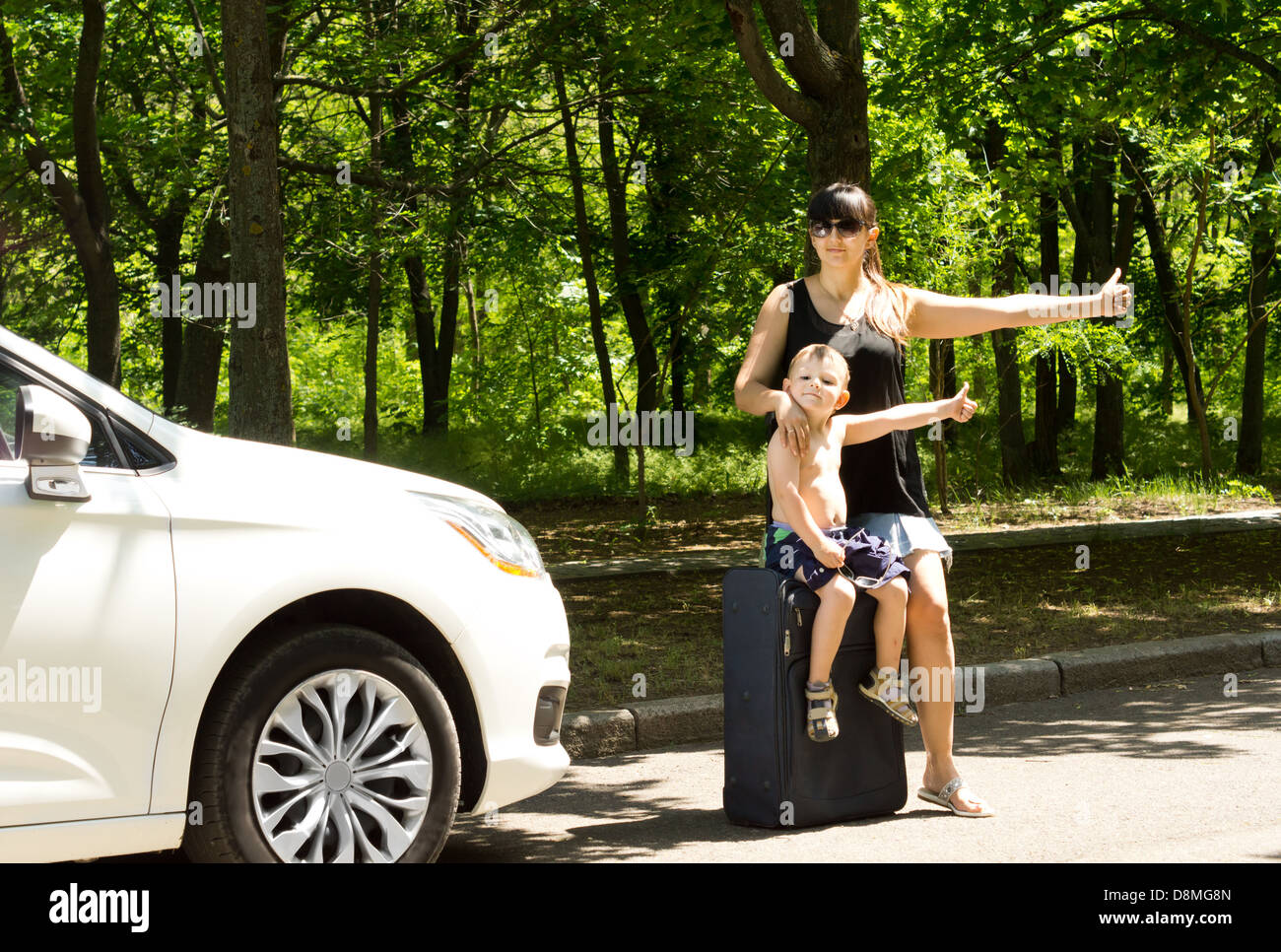 Young mother asking for a lift by the roadside with her young boy
