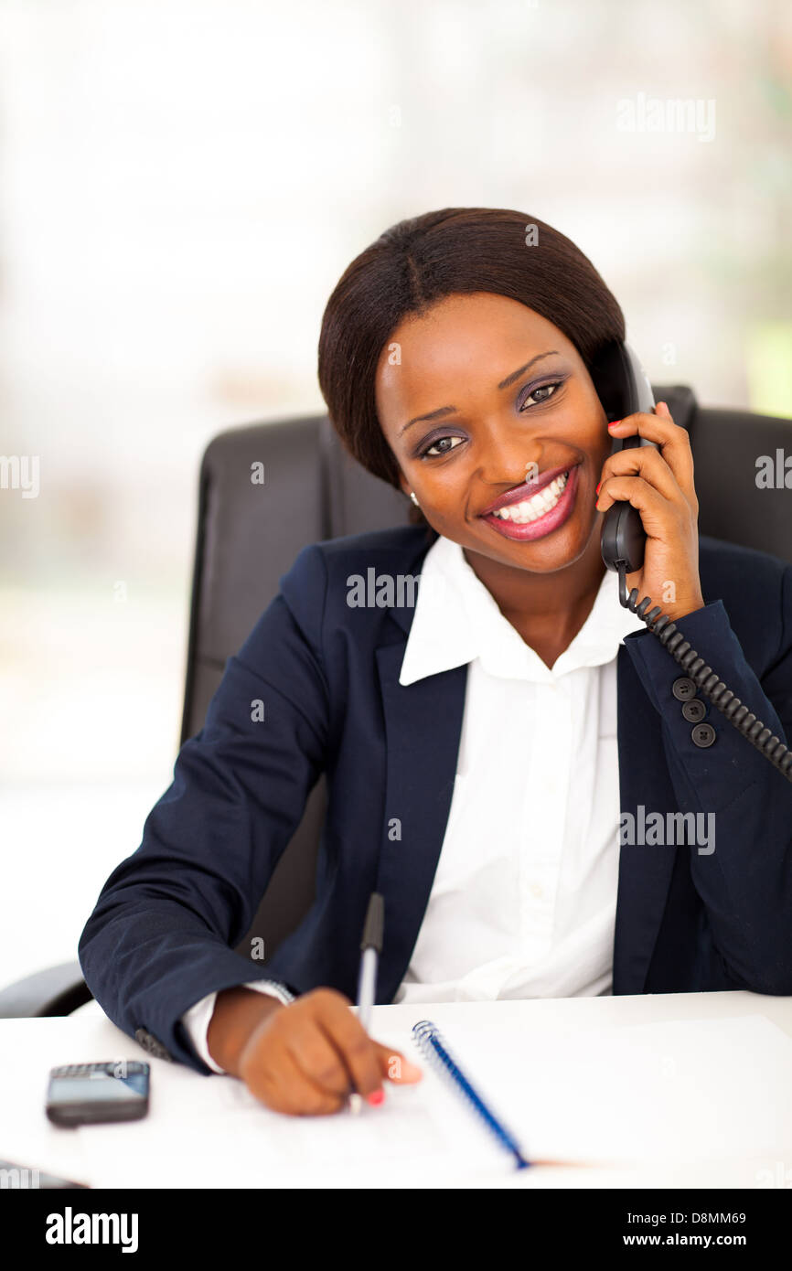 happy African American office worker talking on landline phone Stock Photo