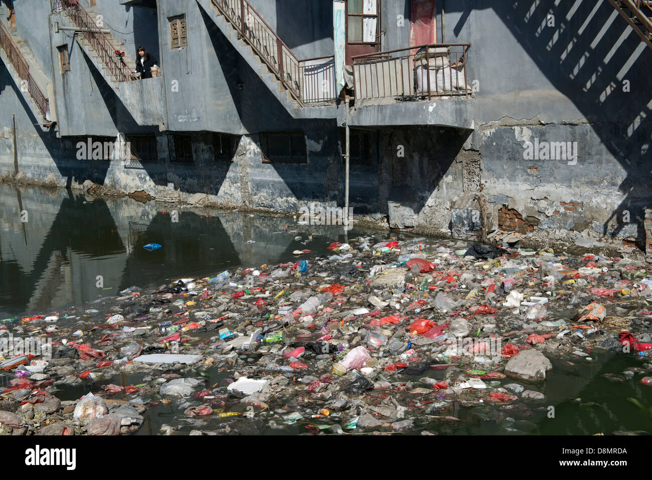 Liu Lu,  a native resident, stands at a balcony over a badly polluted river by garbage and industrial wastewater in Shengfang. Stock Photo