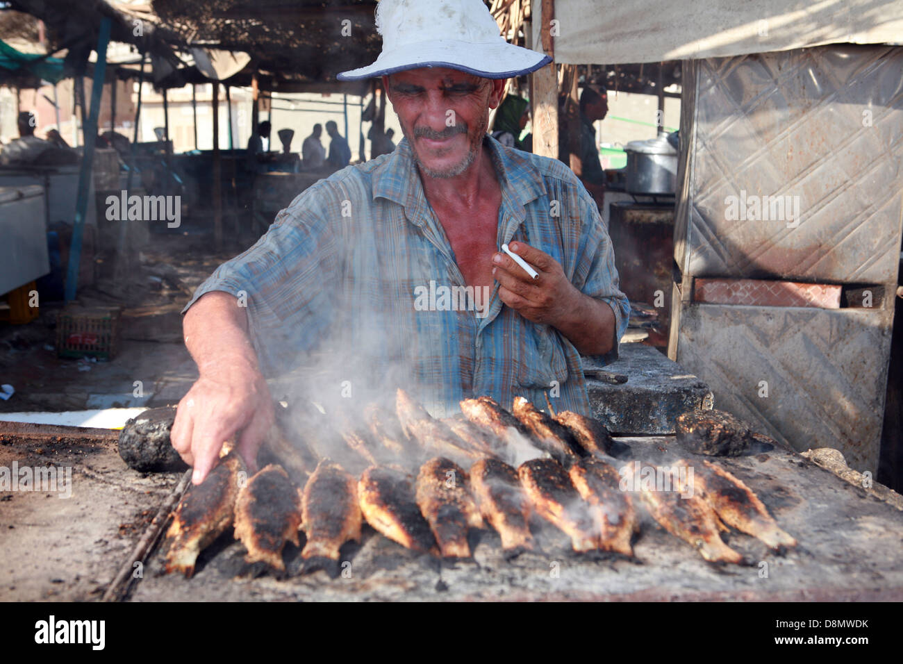 older man is broiling fishes on fish market Stock Photo