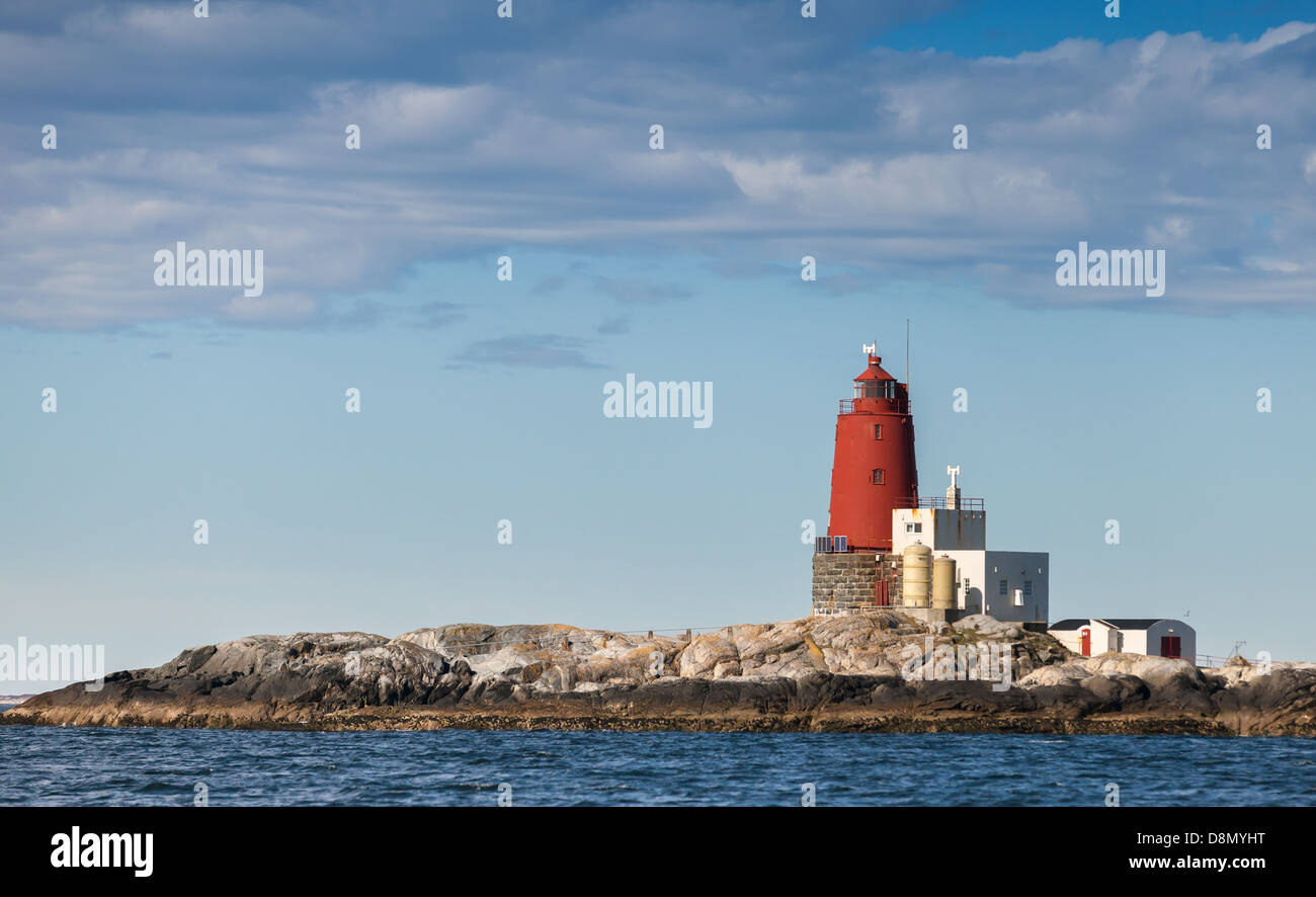 Grinna. Red Norwegian Lighthouse with Large Red Tower on Rocky Island. It was established in 1904 and automated in 1987 Stock Photo