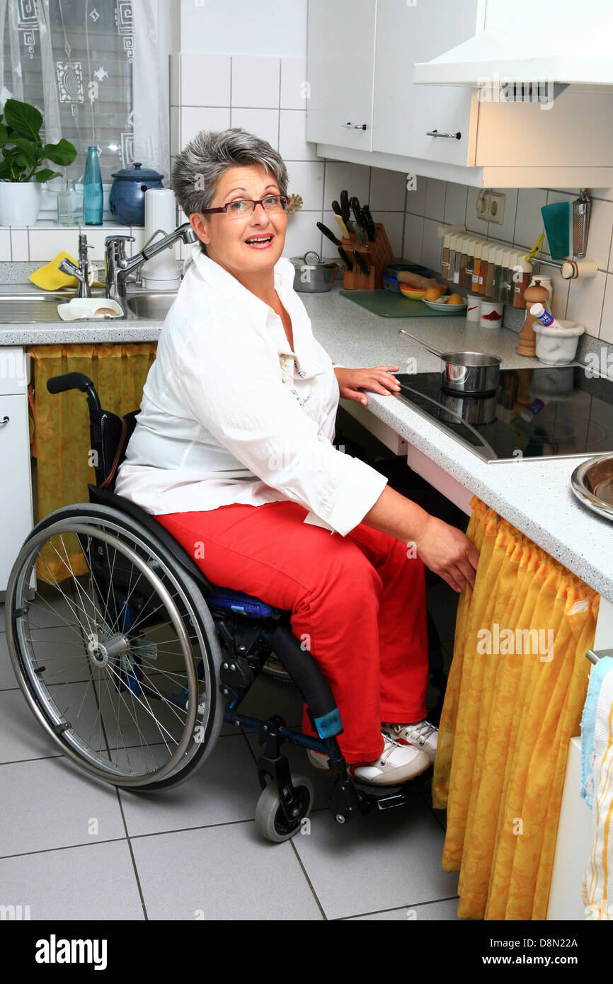 woman in a wheel chair in the kitchen Stock Photo