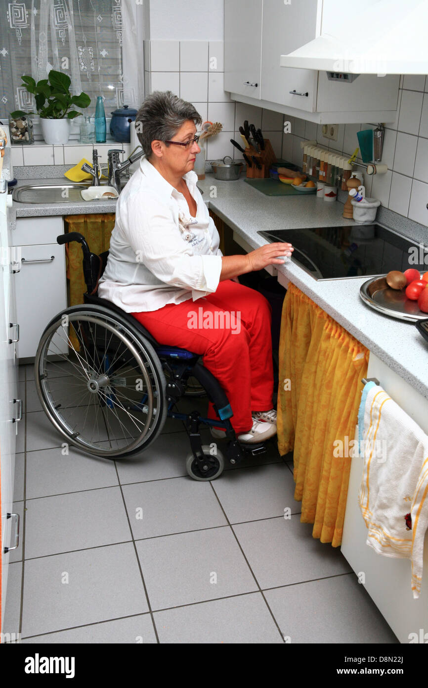 woman in a wheel chair in the kitchen Stock Photo